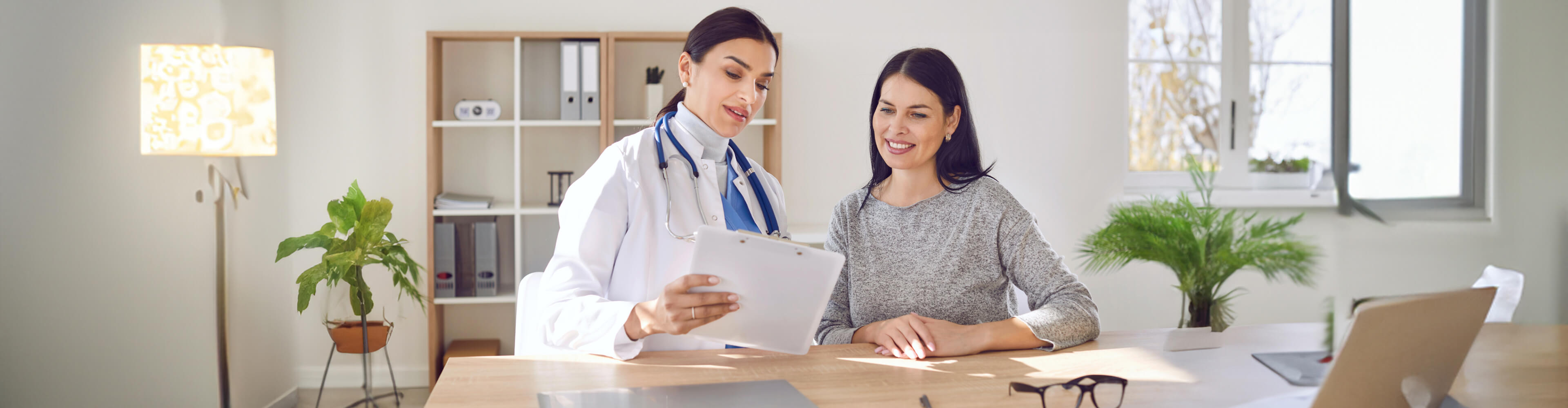 A woman and a healthcare worker discussing a vascular care procedure.
