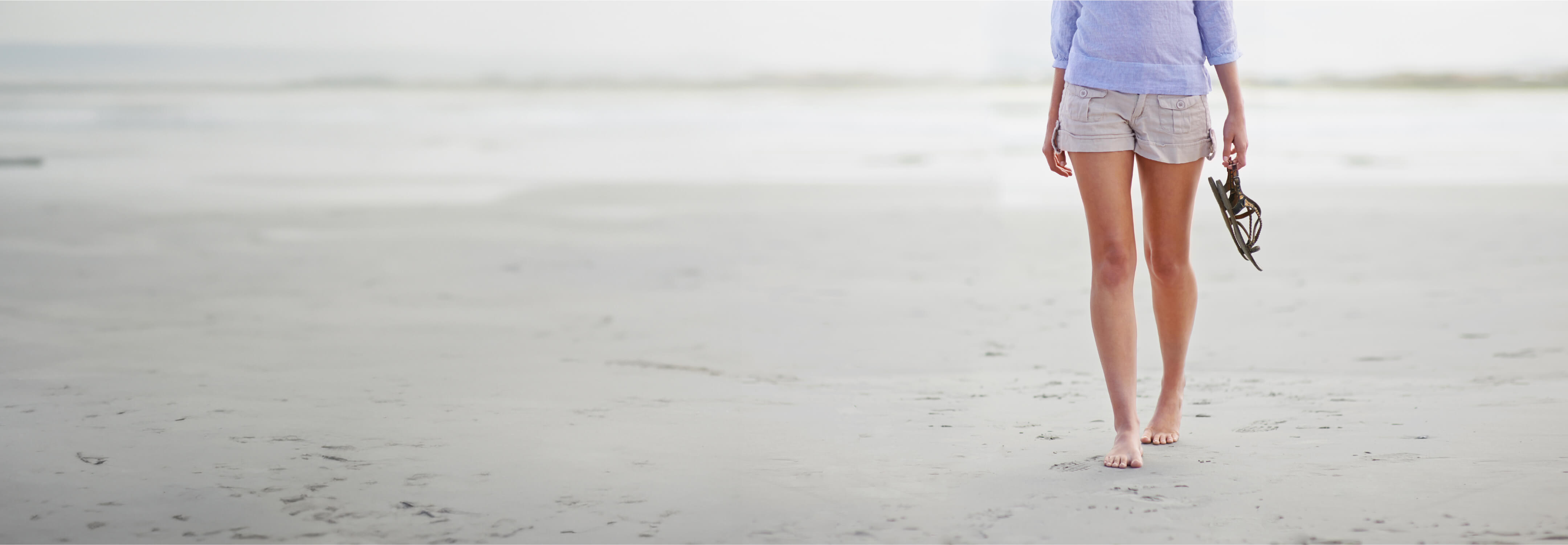 A woman  walking on the beach  with no varicose veins